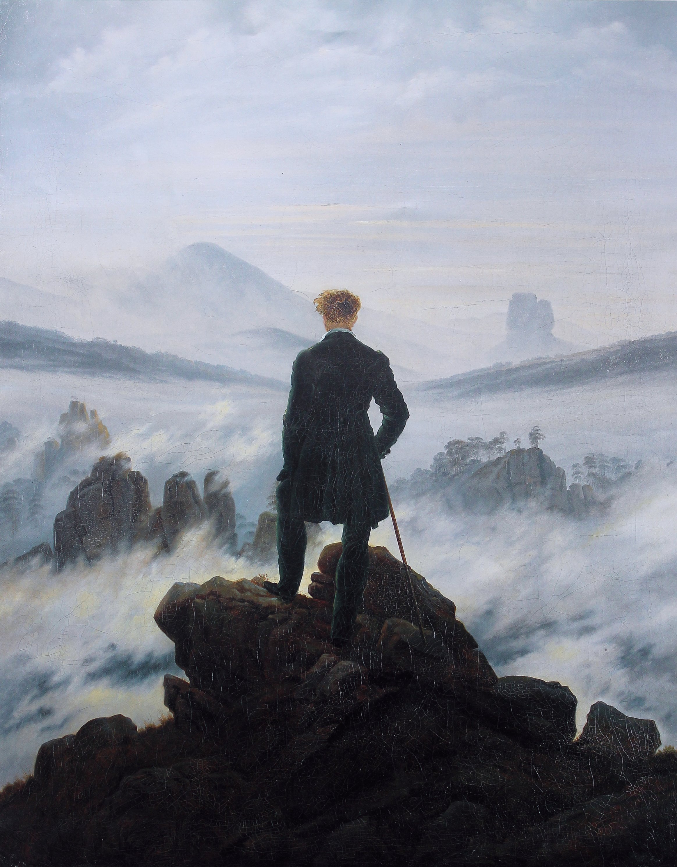 The hiker stands as a back figure in the center of the composition. He looks down on an almost impenetrable sea of fog in the midst of a rocky landscape - a metaphor for life as an ominous journey into the unknown.